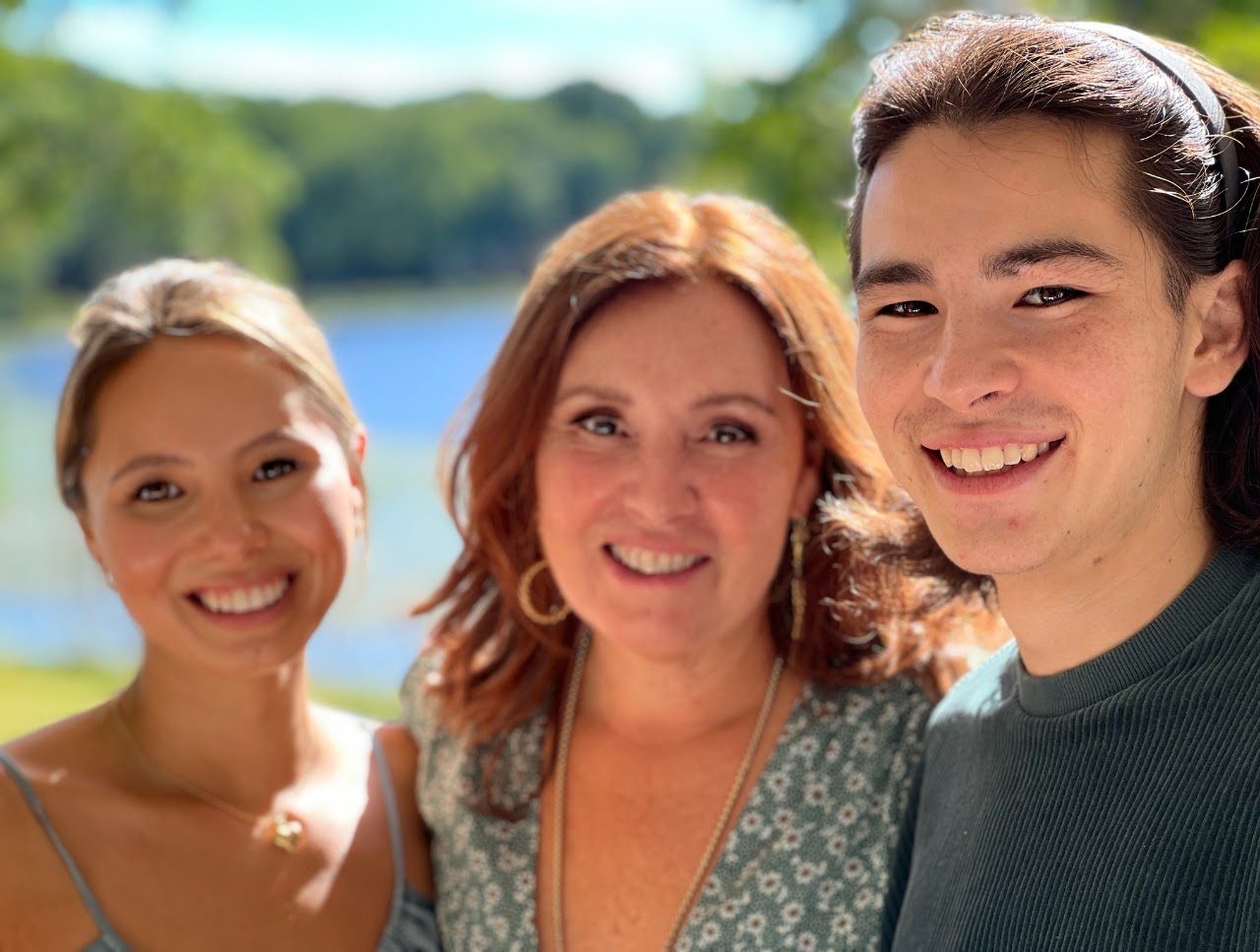 Antoinette smiling with her two children by the lake