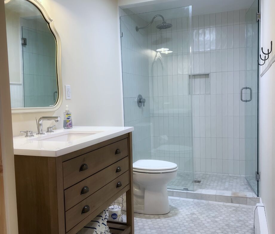 Renovated bathroom with glass walk-in shower and wood vanity