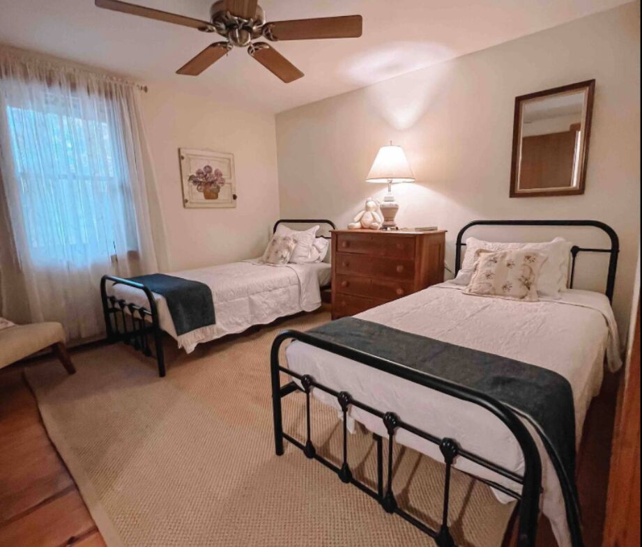 Bedroom with two iron twin beds and a ceiling fan