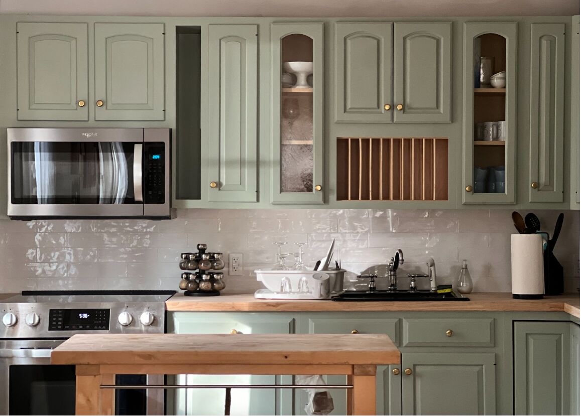 Renovated cottage kitchen, straight on: sage cabinets, open plate rack and butcher-block counters