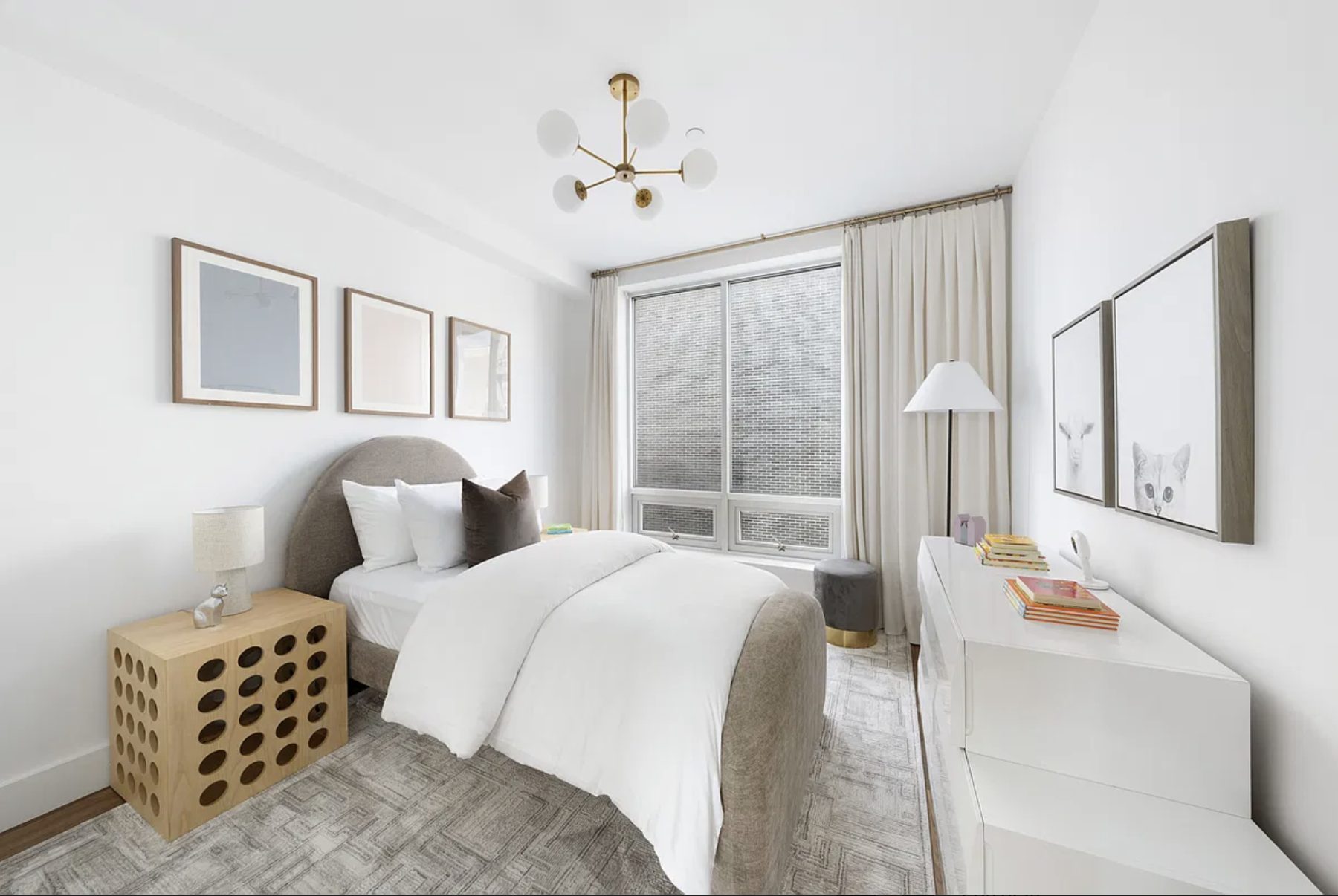 Bright bedroom with an upholstered bed, brass light fixture and soft linen curtains