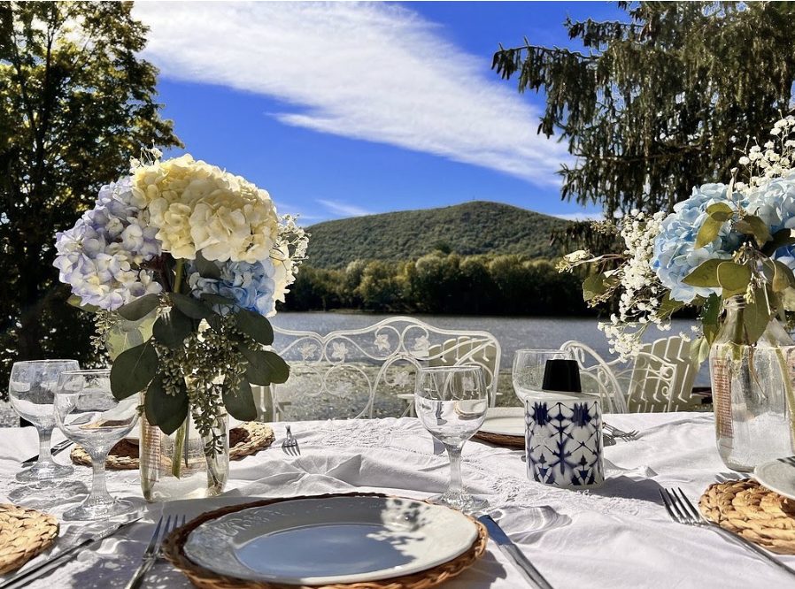 A table set with hydrangeas on the lawn by the lake