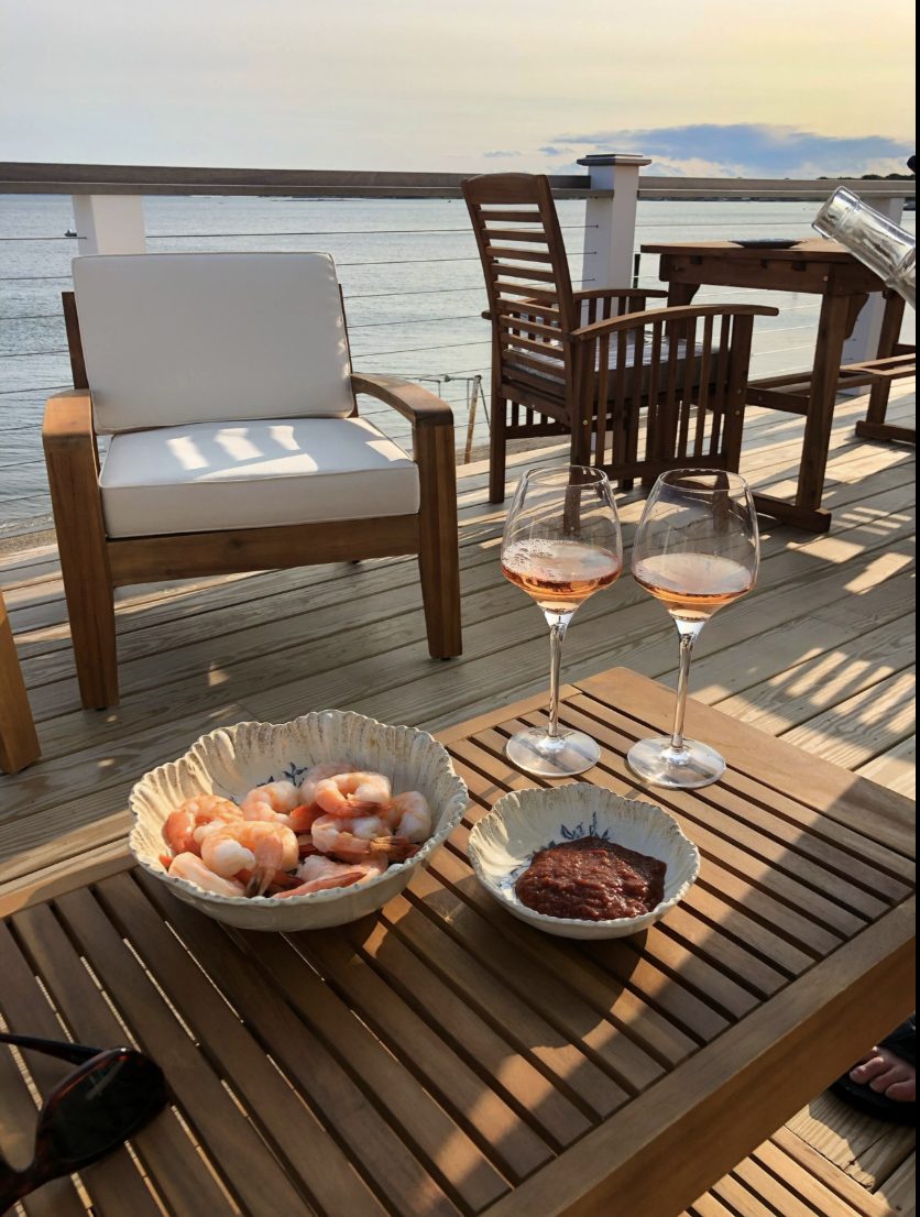 Two glasses of rosé and shrimp cocktail on the deck at sunset
