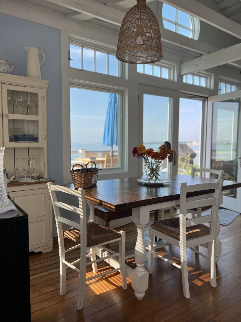 Dining table by tall windows looking out to the water