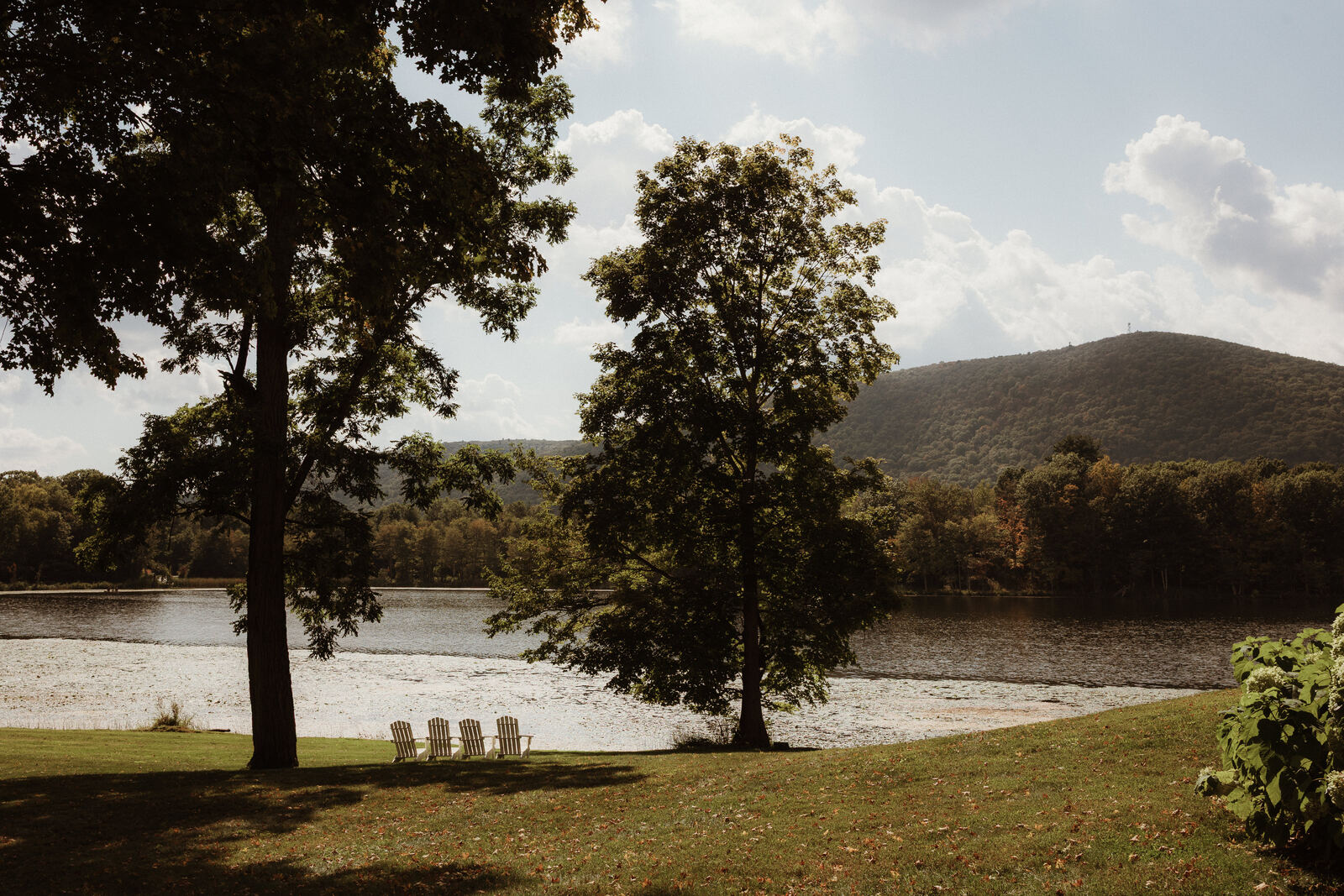 Stissing Lake and Stissing Mountain seen from the lawn, with Adirondack chairs at the water