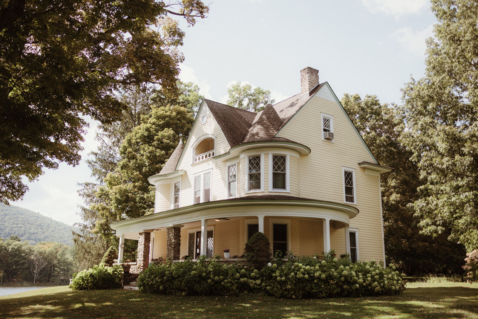 The yellow Victorian main house with its wraparound porch