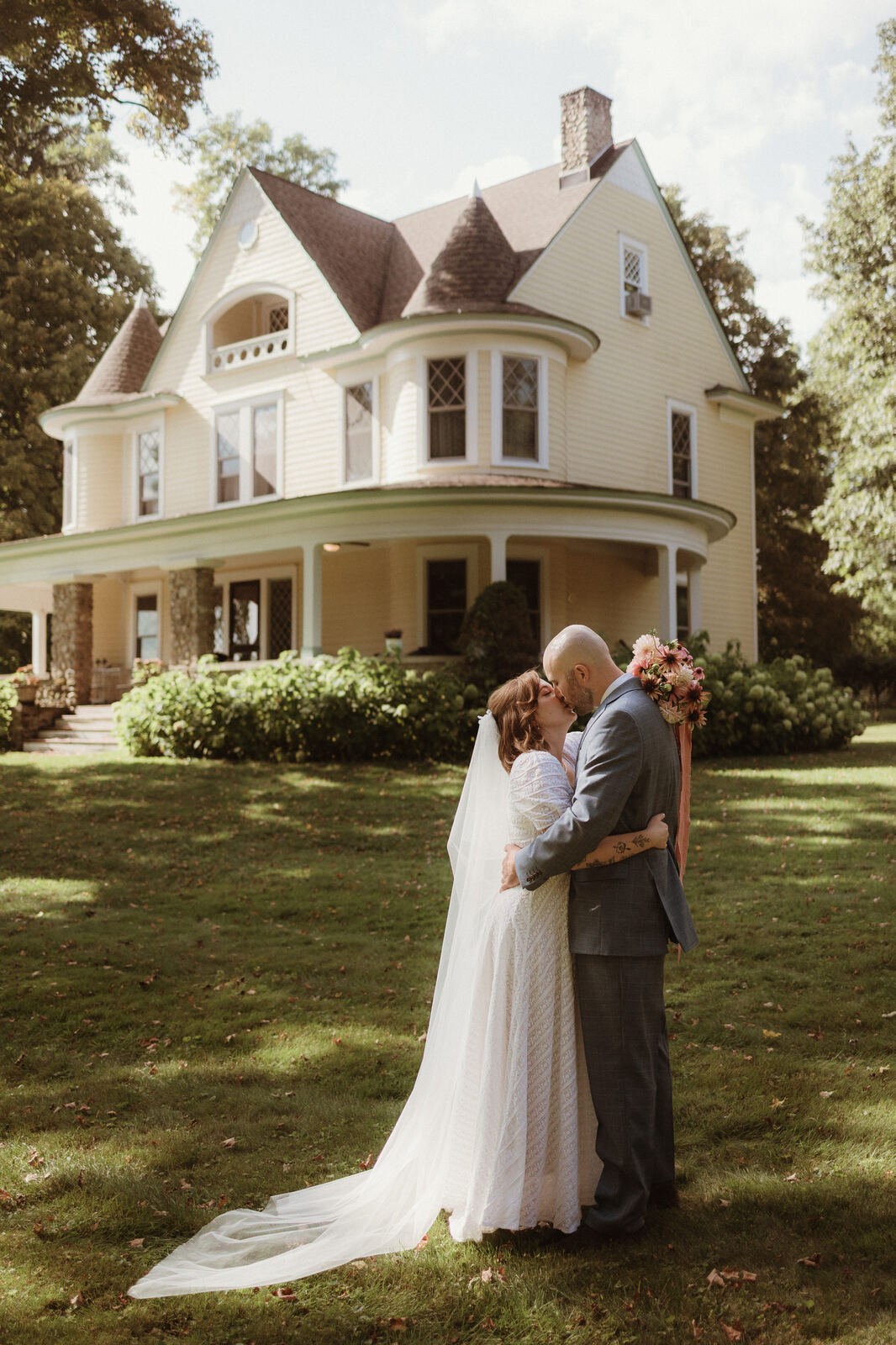 A couple embracing on the lawn in front of the Victorian house