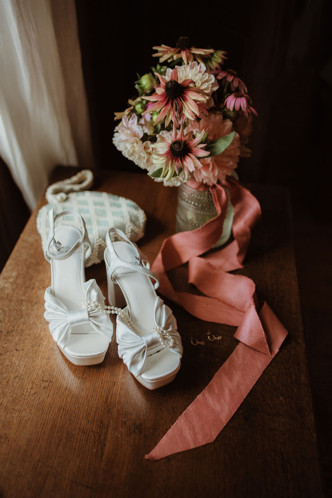 Wedding shoes, bouquet and ribbon on a wooden table