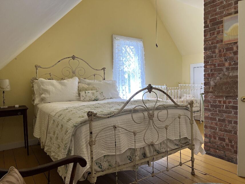 The Yellow Room with a wrought-iron queen bed and a crib